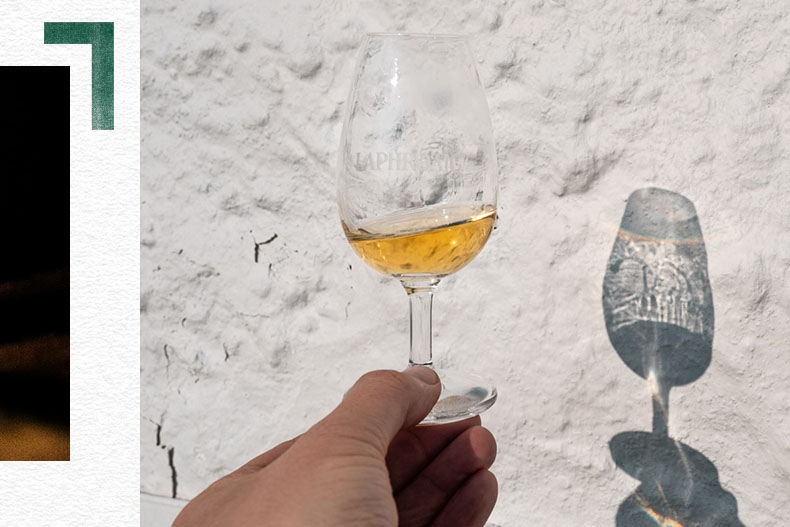 The sun hitting a glass of Laphroaig in front of a wall