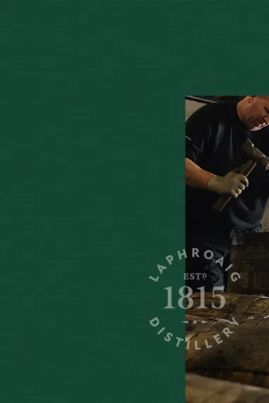 Picture of a man hammering a Laphroaig barrel on dark green background with a Laphroaig Distillery stamp on it