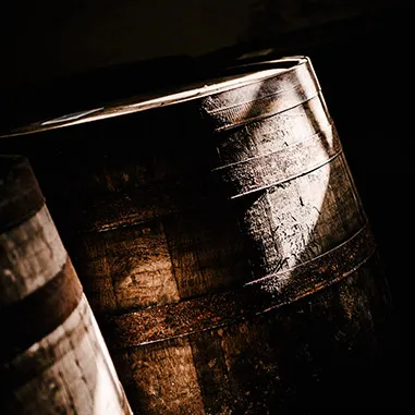 Sunlight hitting a Laphroaig barrel in a shady warehouse corner