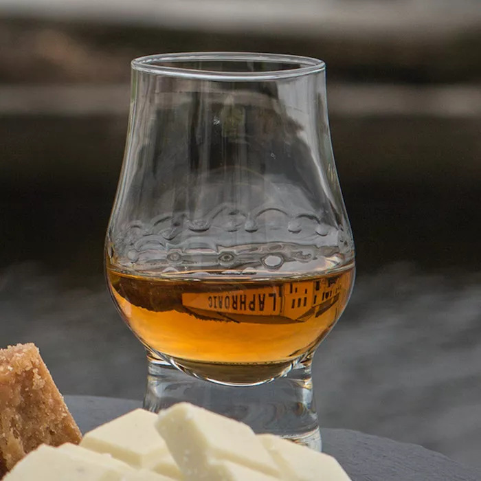 A dram filled with Laphroaig 1815 next to white chocolate pieces and biscuits  