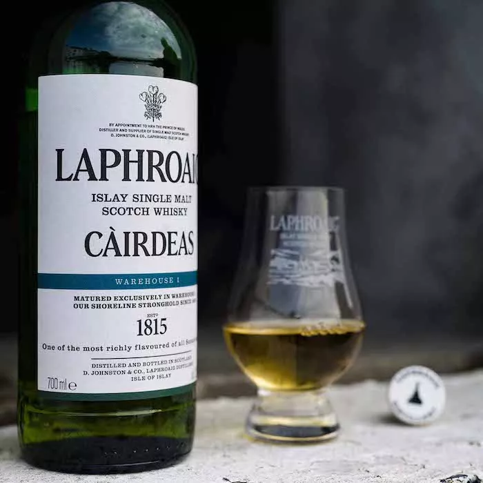 Close up of Laphroaig Cairdeas Warehouse 1 with glass of whisky on stone wall