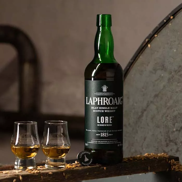 A bottle of Laphroaig Lore with two glasses filled with islay single malt scotch