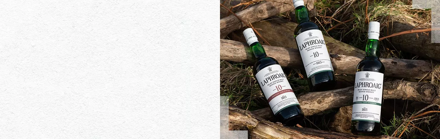 Three bottles of Laphroaig lying on tree trunks