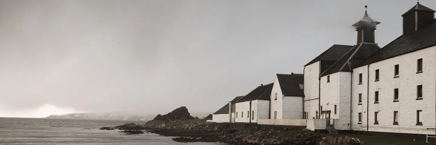 An atmospheric grey sky above Laphroaig Distillery and shore