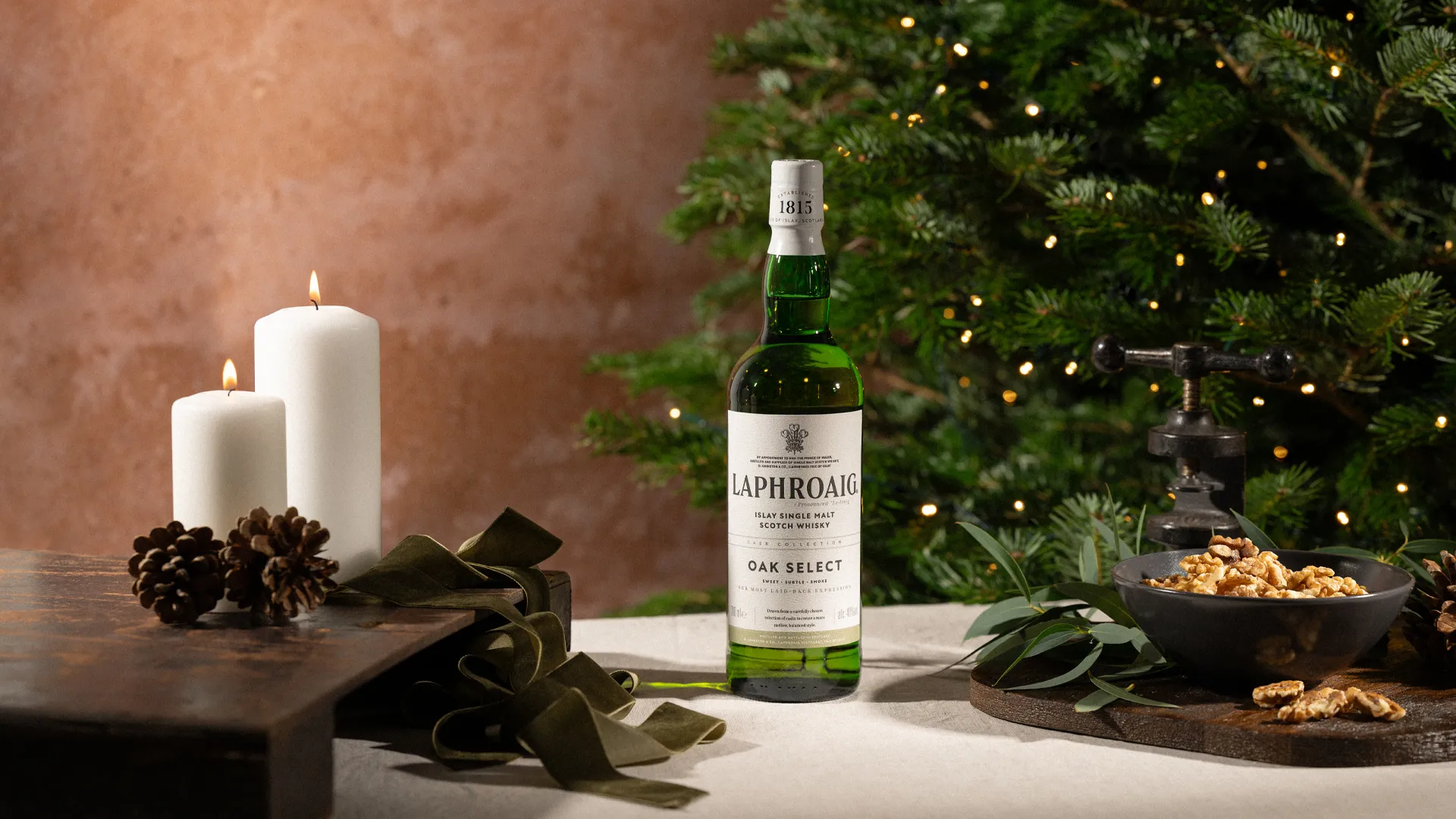 A bottle of Oak Select on a festive dinner table with lit candles and a christmas tree in the background