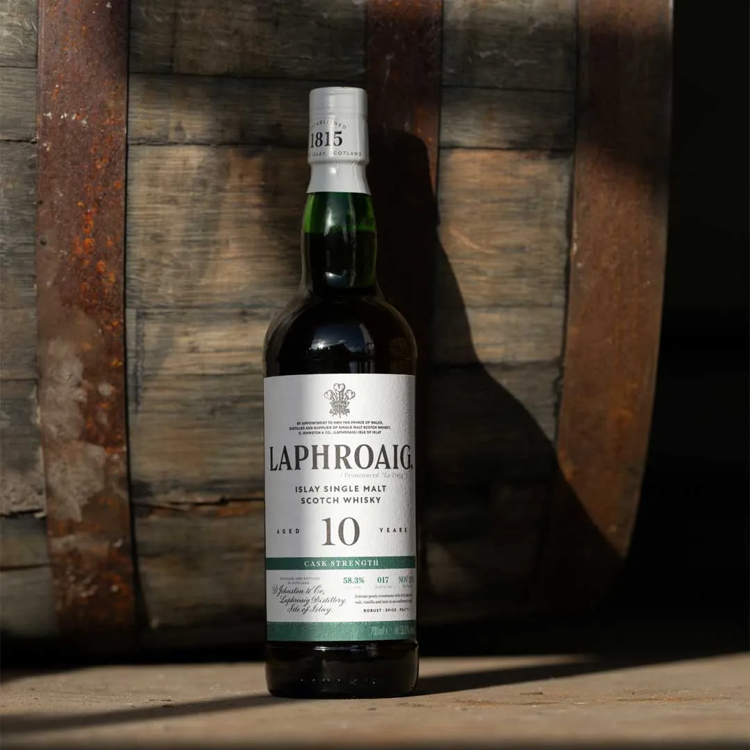 Bottle of Laphroaig 10 Year Old Cask Strength Batch 17 Islay single malt Scotch whisky standing in front of wooden whisky casks.