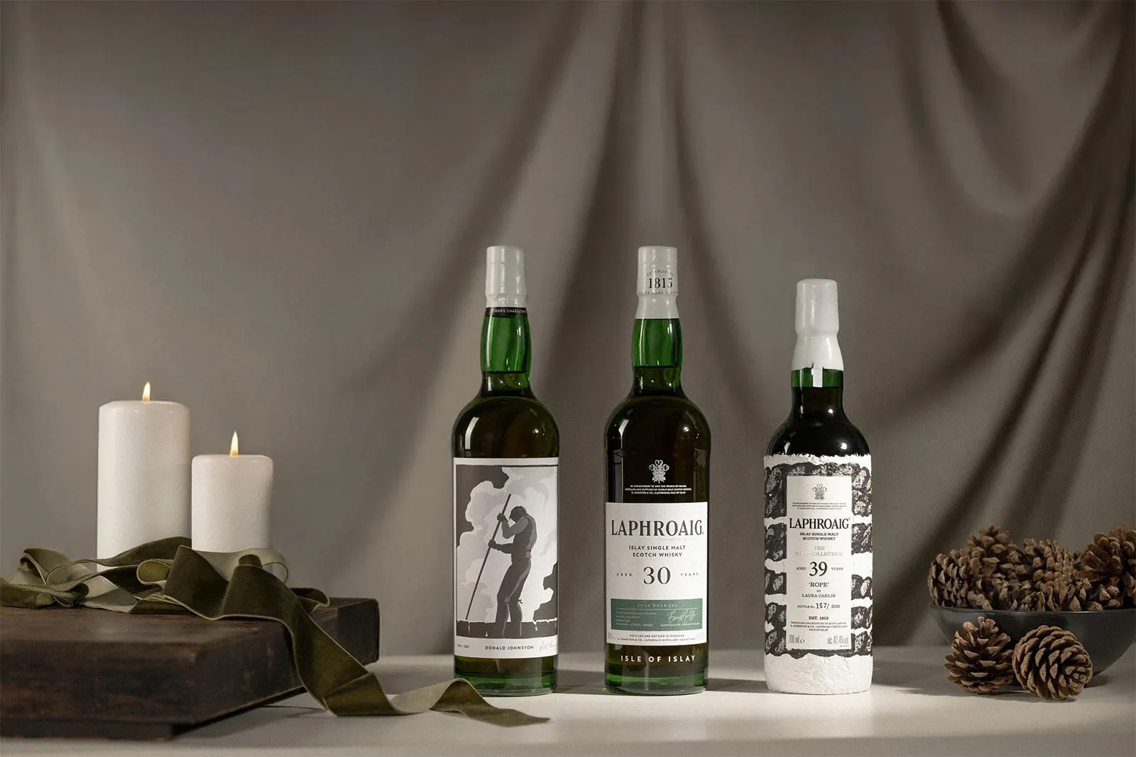 Three Single Malt Whisky Bottles Studio Display Candles Pinecones Laphroaig