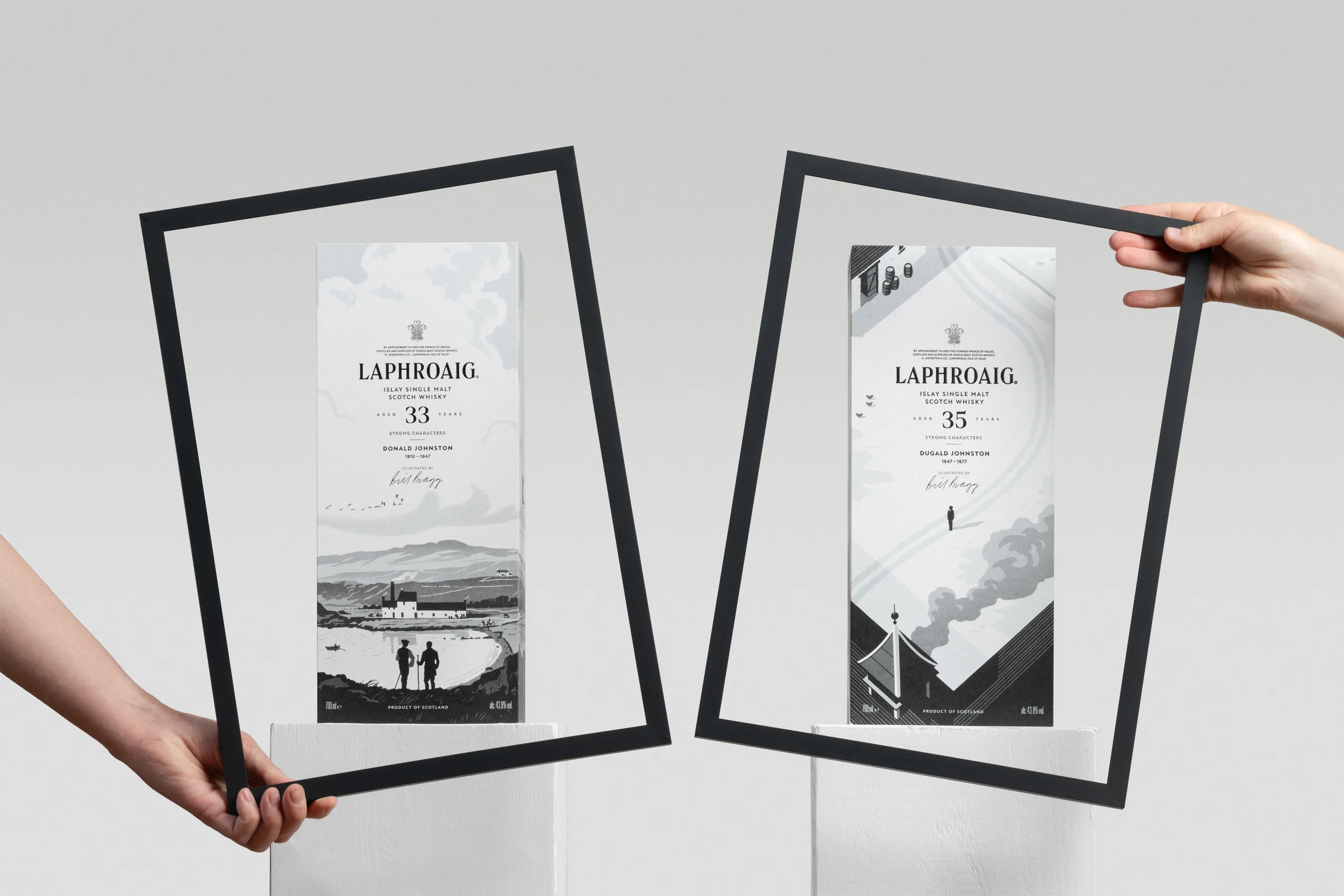 Two hands hold black-framed displays featuring Laphroaig Strong Characters whisky packaging, showcasing the 33-Year-Old Donald Johnston and 35-Year-Old Dugald Johnston releases side by side.